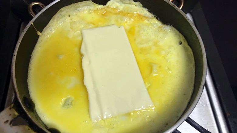 培根芝士蛋卷,待蛋液表面稍凝固，加入奶酪片