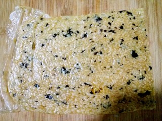 海苔锅巴（剩米饭的华丽转）,将抓办均匀的剩米饭直接倒进保鲜袋中，用擀面杖擀成薄片。