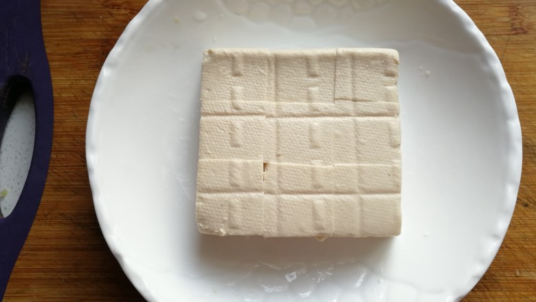 橄榄肉末蒸豆腐,片开后取一块放入盘中，用尖刀切割成小方块