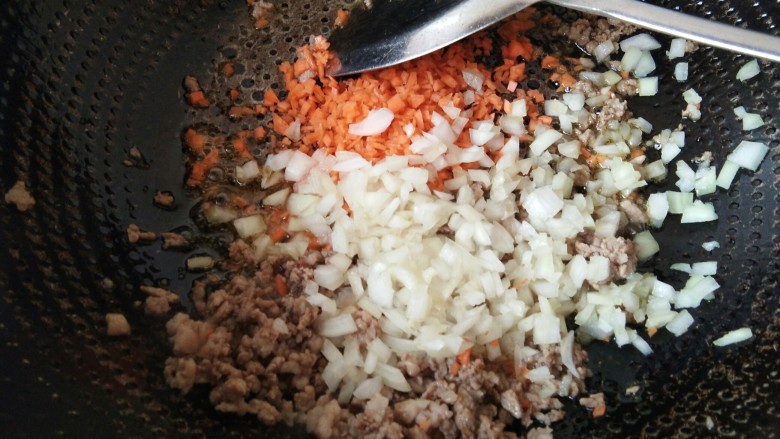 肉末杂蔬太阳蛋蒸饭,肉末炒至变色，加入圆葱丁和胡萝卜丁。