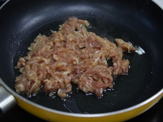 餐桌上最抢眼的一道菜——京酱肉丝,锅里放入适量的花生油，把前面腌制好的瘦肉丝倒入锅中，翻炒
