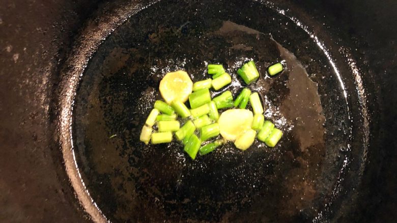 铸铁锅焖蔬菜排骨,铸铁锅中抹油，下姜片和葱白爆出香味。