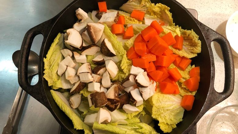 铸铁锅焖蔬菜排骨,加胡萝卜和冬菇丁炒匀。