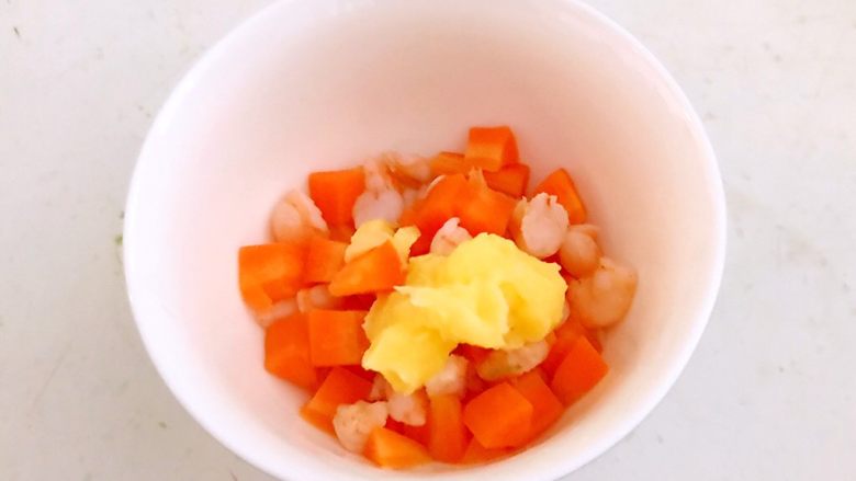 牛油果焗虾仁,把焯好的胡萝卜丁和虾丁捞出来放入碗中，加入1勺自制沙拉酱，加入1克精盐