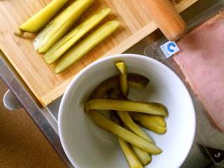 酸黄瓜吐司卷,尽量选取细直的酸黄瓜，切成条，放入碗中备用。