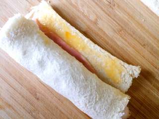 酸黄瓜吐司卷,在留的一条空隙上，刷上鸡蛋液，黏合成卷。