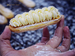 法甜Elysees——天国乐园,取一只手指饼干，将橙花奶酪装进配有曲奇花嘴的裱花袋中，以画圈的手法挤出花纹。