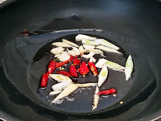 香辣小炒面（制作碱面过程）,锅中放油烧热，放入辣椒，葱白，大蒜炝锅出味。