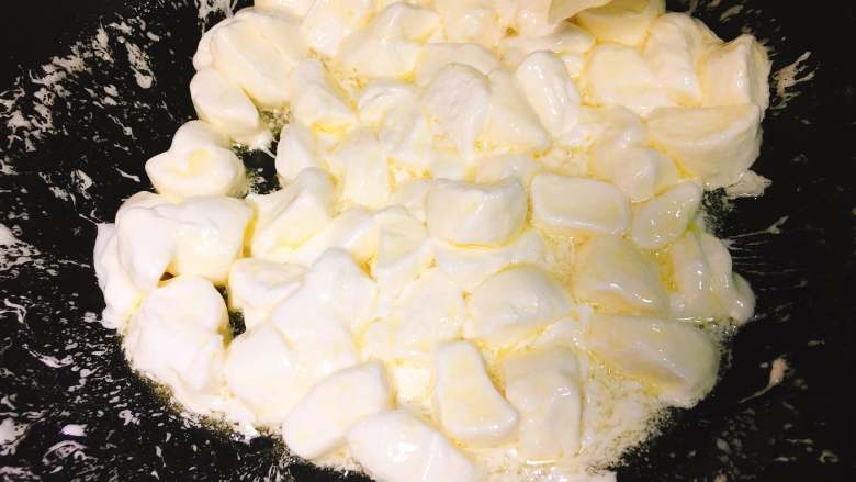 清新抹茶牛乳坚果牛轧糖（棉花糖版）,棉花糖倒入到黄油中，用刮刀继续搅动，同时用压拌的手法辅助融化。