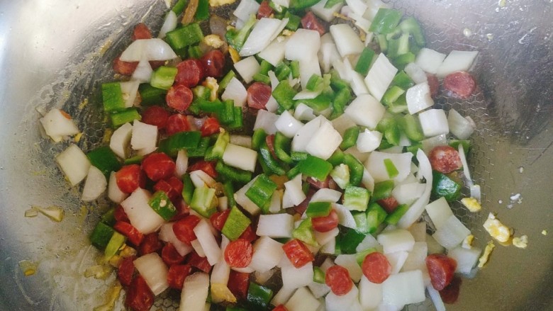 腊味菠萝炒饭,锅中放油，下腊肠，洋葱，青椒。煸炒至熟。