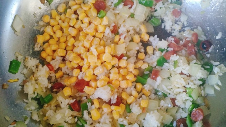 腊味菠萝炒饭,米饭均匀的搅散，加入玉米粒翻炒均匀。