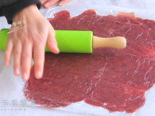 猪肉脯,上面铺一张保鲜膜，擀面杖把肉馅擀成薄薄的片。撕去保鲜膜，烤纸放烤架上准备开烤，烤箱预热180度，先烤15分钟。