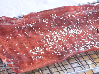 猪肉脯,肉变色变熟，体积略缩。撕去烤纸，直接放烤架上，将两面都用刷子均匀的刷上蜂蜜，撒上白芝麻~