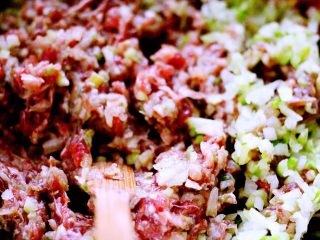 做年货-牛肉萝卜蒸饺,把切碎的葱花和萝卜放入搅拌好的肉馅里