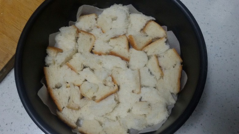 苹果吐司布丁,在烤盘里铺上油纸，将撕好的吐司均匀放进烤盘里