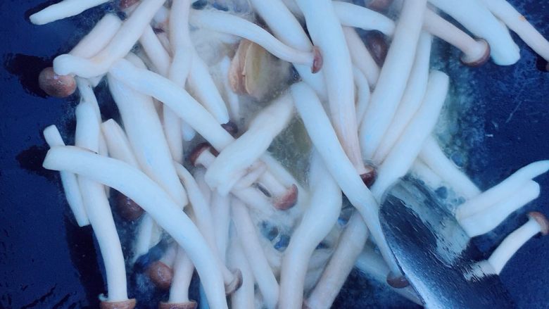 蟹味菇炒牛肉卷,差不多大火煮1分钟，待蟹味菇翻炒出汤汁后，放入适量的盐。翻炒