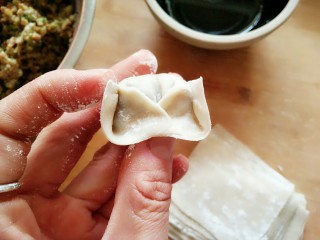 香菇鲜肉大馄饨,将馄饨皮的两个角叠加在一起，沾水捏紧。