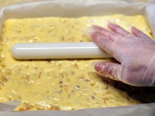 芒果干花生牛轧糖,将混合物倒入事先备好的模具中，用擀面杖压平整，放冰箱冷藏30分钟。