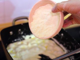 芒果干花生牛轧糖,小火熬至棉花糖与黄油充分融合后分三次倒入芒果粉与奶粉，搅拌均匀。