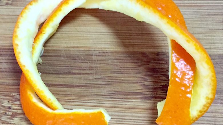 橙篮子,把长条橙皮分成两部分，编织成如图形状，篮子把就完成了，如不好固定可以用短短的牙签固定两端即可
