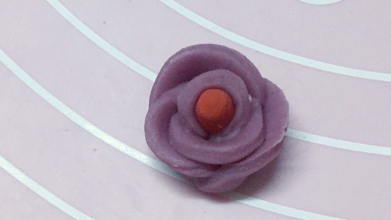 情侣鹅,另取一小点红色面搓一根小圆柱做花芯，再把切开的紫色花瓣一片片都粘贴在红色花芯上，稍微整理下，做成一朵小花，如上图。