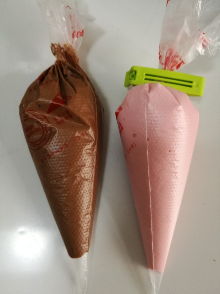 法式马卡龙,装入裱花袋，我同时做了个粉色的，方法一样只是不加可可粉，加了一点粉色素。把可可量换成杏仁粉即可。