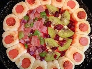 花边双拼披萨,在涂好番茄酱的面饼上面，一边铺上炒好好的培根和蔬菜，一边铺上切好的猕猴桃片和蔓越莓。