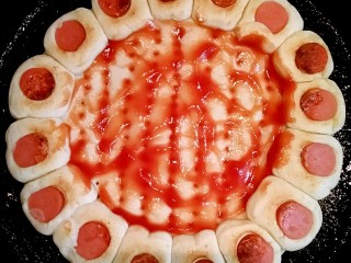 花边双拼披萨,待花边这面烙的微黄后，翻转，在面饼里面涂上番茄酱。