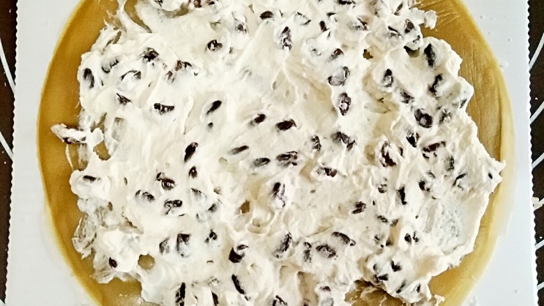 抹茶蜜豆千层蛋糕,在一层面皮上均匀铺满蜜豆奶油馅。