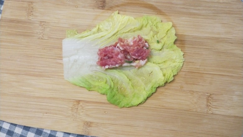 美味和颜值并存的白菜包肉,取一片白菜叶摊开，舀一勺肉末放到菜叶的中间