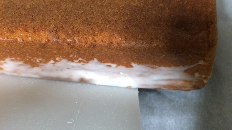 淋面柠檬香草磅蛋糕,首先，将蛋糕转移到烹饪板上，并使用一张卡轻轻将一个玻璃箭头应用于侧面的底部。