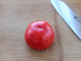 番茄肉酱螺旋意面,将番茄洗净在表面划十字