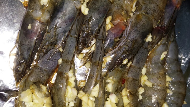 蒜蓉烤虾,然后把腌好的虾放在烤盘上，垫上锡纸，把蒜末填到虾背里