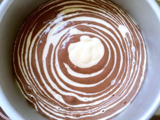 斑马纹酸奶蛋糕（8寸）,准备两个大小相同的勺，用小勺舀一勺原色面糊倒在模具中间，之后再舀一勺可可面糊倒在原色面糊上，反复倒入两个颜色的面糊，直到将面糊全部倒入模具内