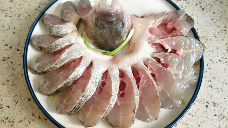 孔雀开屏鱼,腌好的鱼放盘子里摆出孔雀的造型，鱼头竖在中间，鱼尾塞在鱼头里面