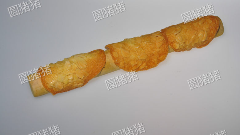 简单又美味的——杏仁瓦片酥,烤好的饼干乘着有些微热时，放在擀面杖上，折成弯形，放凉至变硬。