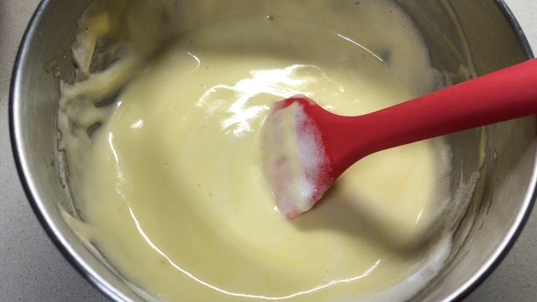 戚风杯子蛋糕,三分之一的蛋白霜加在蛋黄糊里混合均匀。