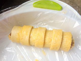 香蕉竹节卷,将卷包裹后，在鸡蛋液中滚一下，使其均匀涂上蛋液。