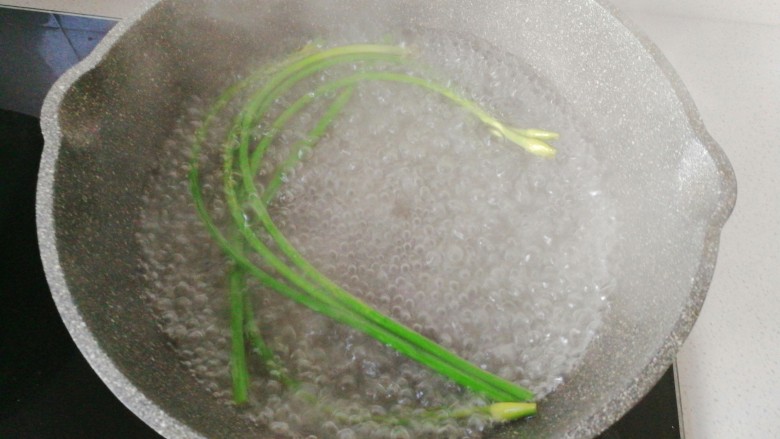 年菜~黄金福袋,锅中烧热水，先放蒜苔焯下水