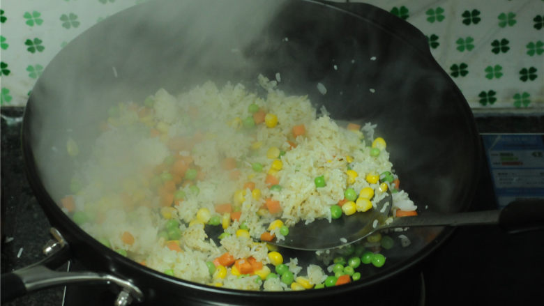 黄金蔬菜炒饭,汆烫好的蔬菜粒倒入锅里，一起翻炒均匀