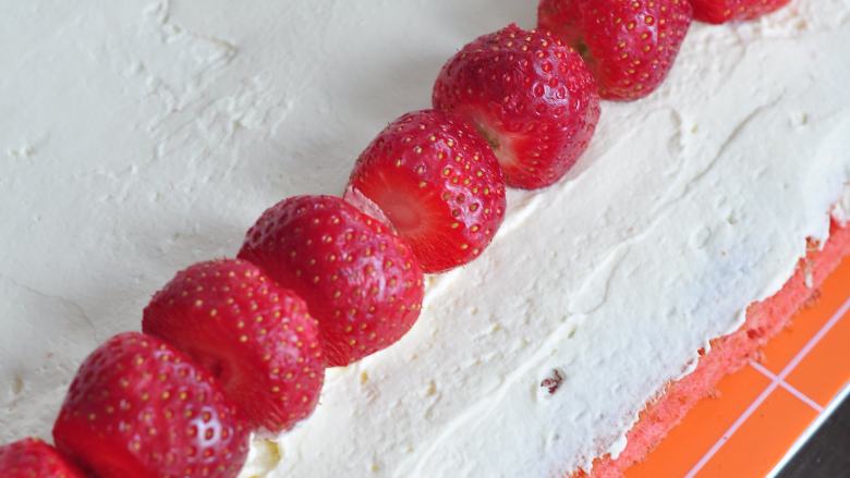 草莓蛋糕卷,蛋糕出炉后脱模，背面抹上打发的淡奶油，将<a style='color:red;display:inline-block;' href='/shicai/ 592'>草莓</a>去掉上下部分，摆在奶油上，慢慢卷起，放冰箱冷藏一小时定型。