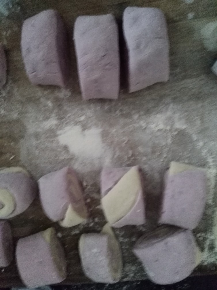紫薯馒头,将白面团，紫面团，擀面皮，叠起来，卷好长条，用刀切，如图