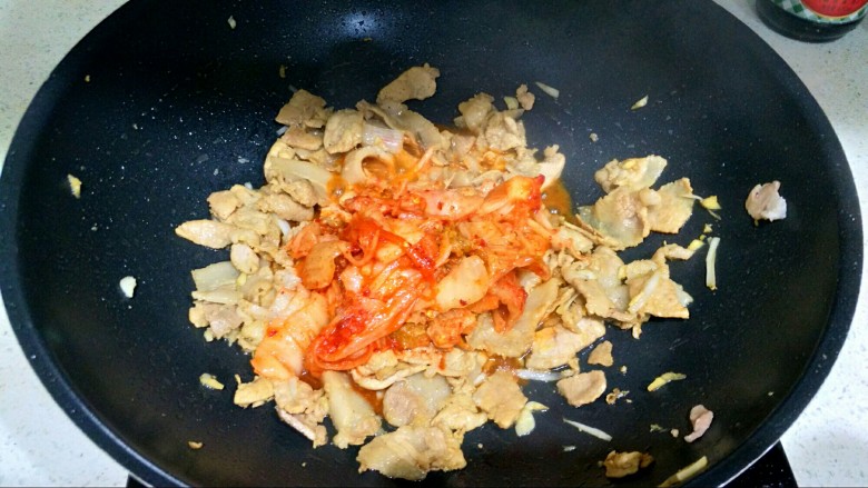 辣白菜五花肉,把辣白菜下锅，大火翻炒2分钟，让肉和辣白菜充分融合。
