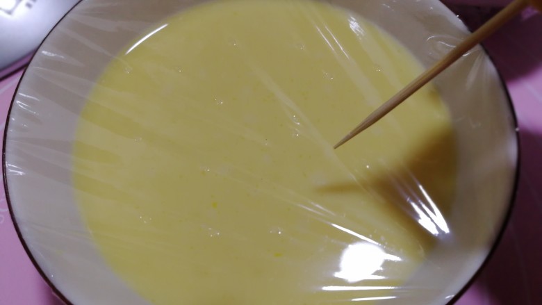 牛奶鸡蛋羹,牙签儿在保鲜膜上面戳上小孔。
