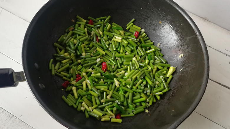 【蒜薹炒鸡丁】,下入蒜薹段翻炒至颜色变深绿，至断生