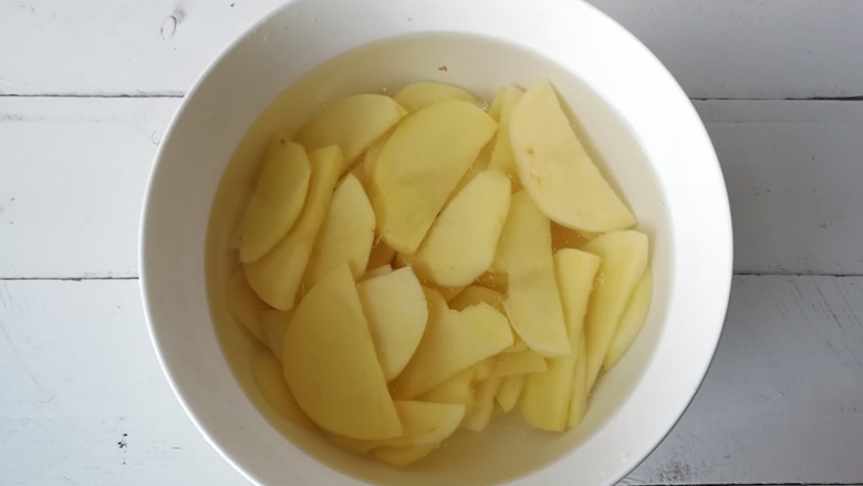【干煸土豆片】 ,将土豆切成0.5厘米厚的片，再放在清水中投洗去淀粉，捞出沥净水待用