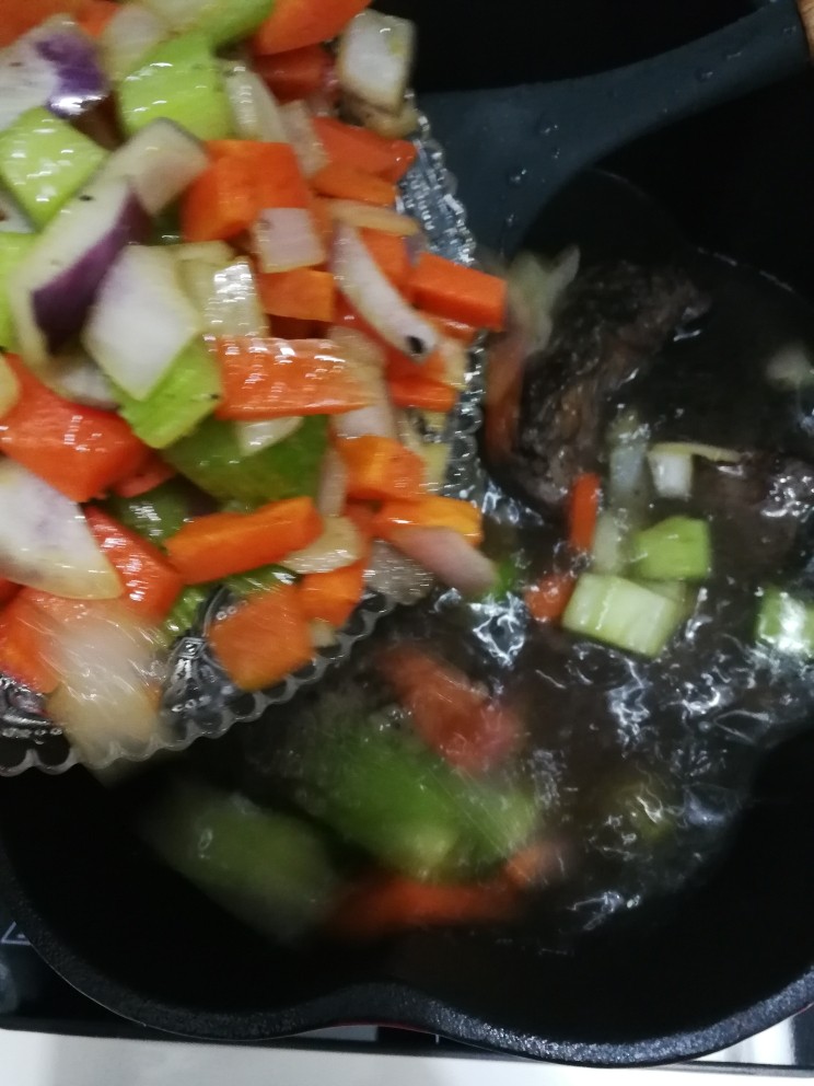 红酒炖牛尾,把煸炒好的蔬菜丁加入牛尾汤里。