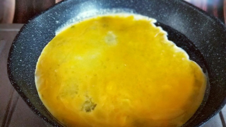 韭菜鸡蛋水饺#附加韭菜不出水秘诀#,起油锅，又热时倒入蛋液，小火煎蛋饼，待蛋液凝固后再将鸡蛋饼切碎。