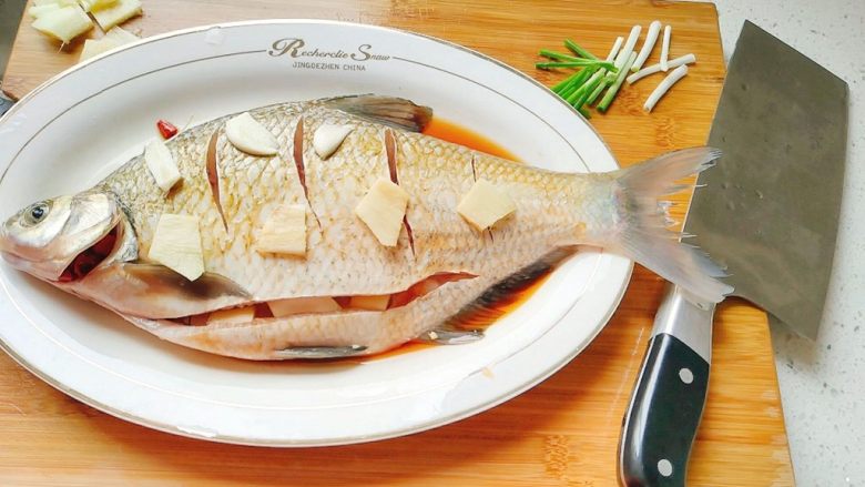 鱼跃龙门年年有余+红烧鳊鱼,用姜片把鱼擦擦，然后铺上姜片，蒜片，腌制半小时。中间的时候，记得翻面，腌下另一边。