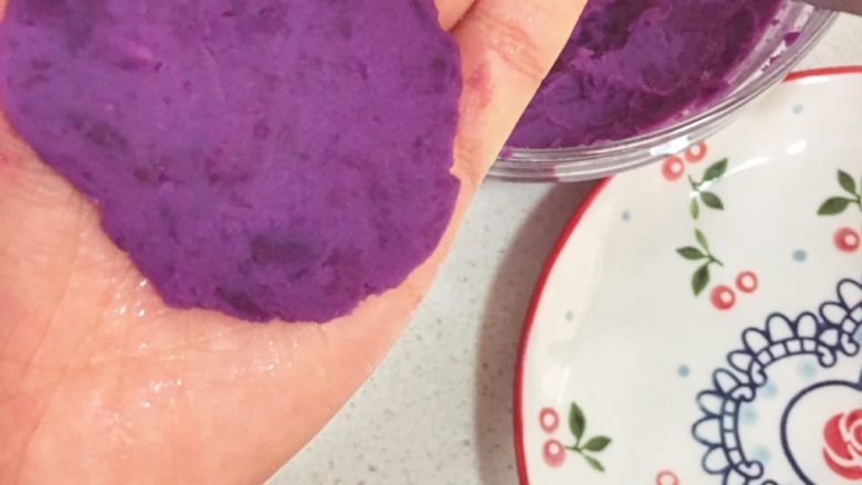 宝宝辅食10M➕：紫薯大米奶酪丸,手上略微沾上一些水，取一勺紫薯泥，压平
